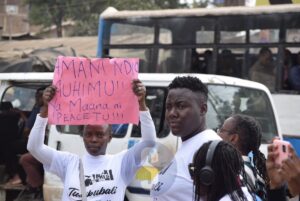 Mercy Garcia illustrates boxing moves to a passerby Purity Gathoni of advocating for a peace ahead of the August 2022 polls while on a procession at Kibera on July 27, 2022. Image: CHARLENE MALWA